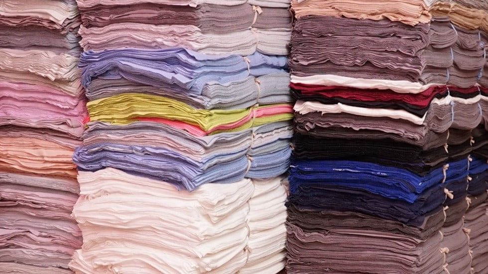Stoc de material din bumbac nou, așezat în teancuri pe culori